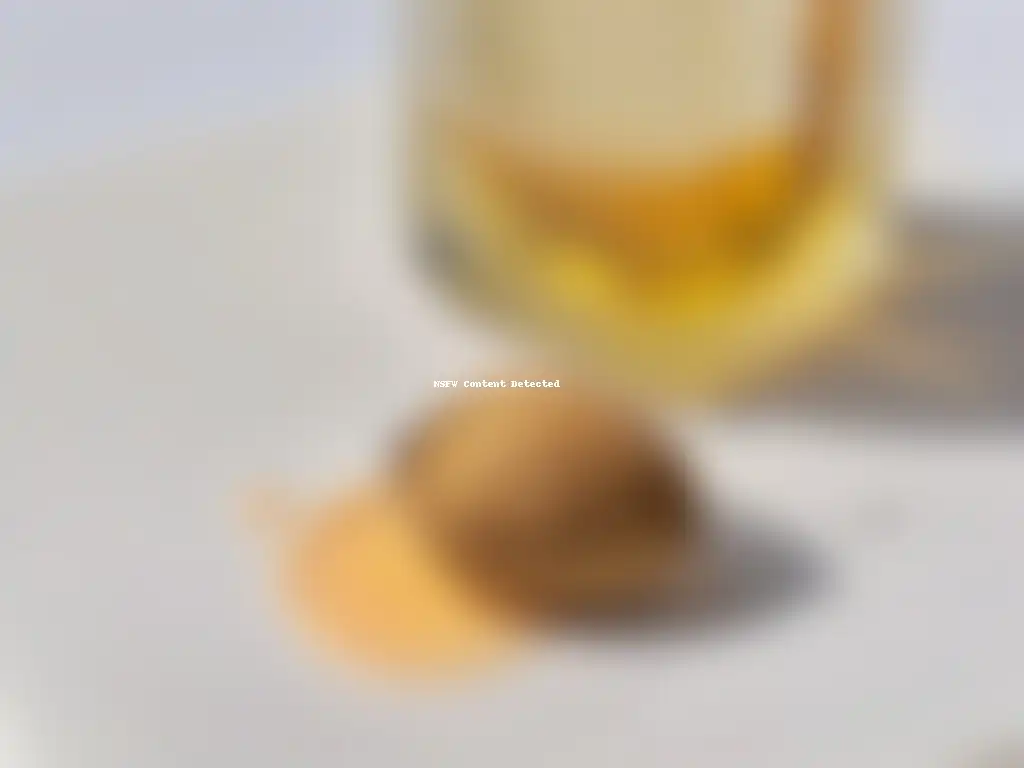Un almendra siendo exprimida para liberar una gota de aceite dorado, resaltando la pureza y beneficios del aceite de almendras